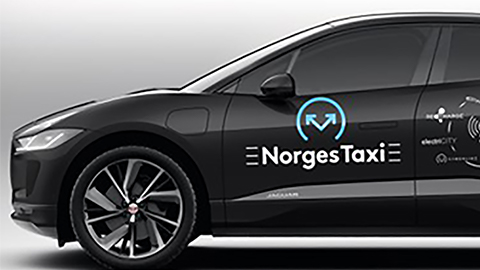 The front of a black car. Text on the side of the car reads: "Norges Taxi".